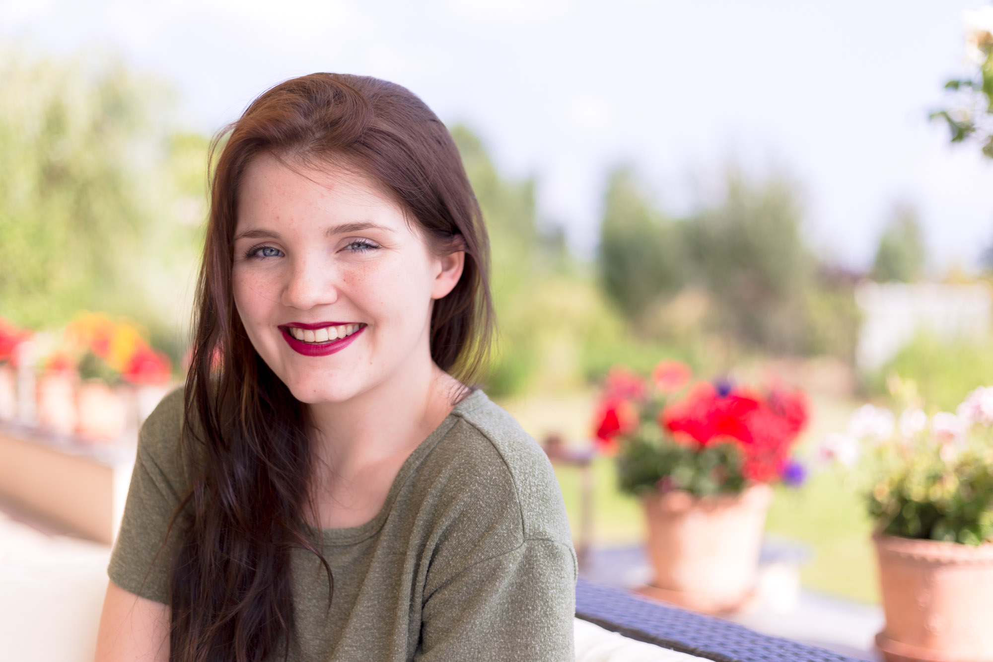 Mädchen mit roten Lippen und roten Blumen im Hintergrund